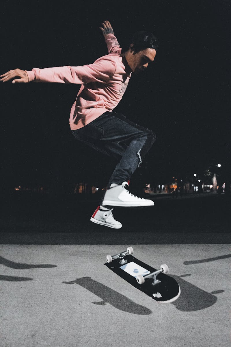 Skateboarder performing a flatground trick at night
