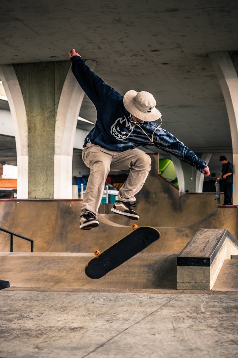 Skateboarder doing a kickflip under a concrete bridge