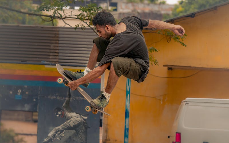 Skateboarder doing a street trick near a yellow wall